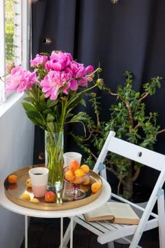 Summer breakfast on balcony. Two cups of drink, bouquet of pink peonies, old Stock Photos