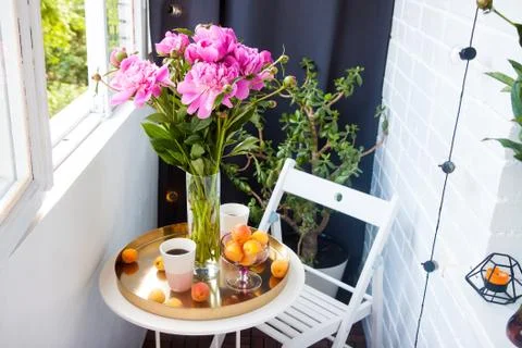 Summer breakfast on balcony. Two cups of drink, bouquet of pink peonies, old Stock Photos