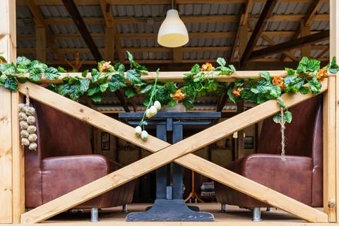 Summer cafe with brown leather sofas and wooden railing, artificial flowers f Stock Photos