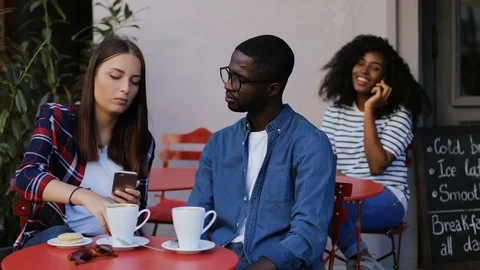 Summer cafe with visitors. Group of young visitors sitting at tables on terrace Stock Footage 81836106