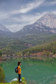 Summer camp. a boy with a backpack looks at a beautiful mountain lake. Relaxe Stock Photos