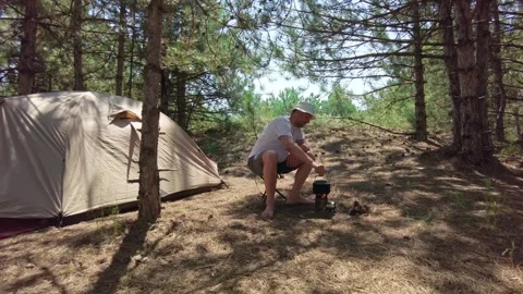 Summer Camping Scene: Man Boiling Water on Wood Fire in Pine Forest Stock Footage 287715266