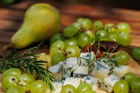 Summer cheese board with pear, grapes and dates.. Stock Photos