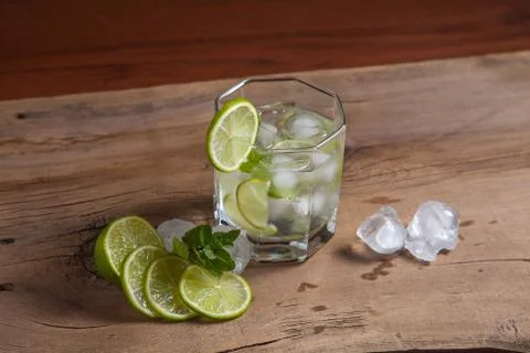 Summer cocktail mojito in glass, fruits and ice cubes on wooden background.. Stock Photos