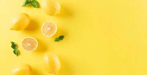 Summer composition made from oranges, lemon and green leaves on pastel yellow Stock Photos