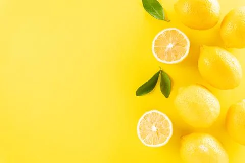 Summer composition made from oranges, lemon and green leaves on pastel yellow Foto stock