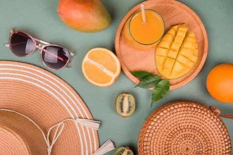 Summer composition. Straw hat, mango, orange, kiwi on green background. Flat  Stock Photos