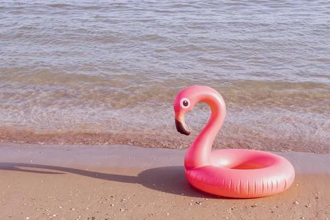 Summer concept background. Pink inflatable flamingo in blue ocean water for s Stock Photos