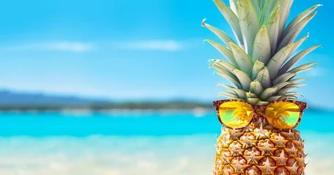 Summer concept funny Pineapple fruit with sunglasses on beach sand against Stock Photos