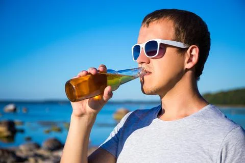 Summer concept - handsome man drinking beer on the beach Stock Photos