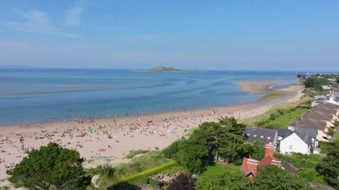 Summer Crowd on Irish Sand Spit beside Seaside Homes, Aerial Fly Along Stock Footage 338076499