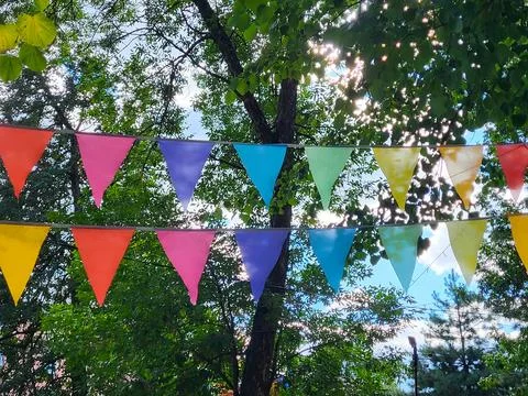 On a summer day, triangular colorful flags hang in the park above the alley 스톡 사진