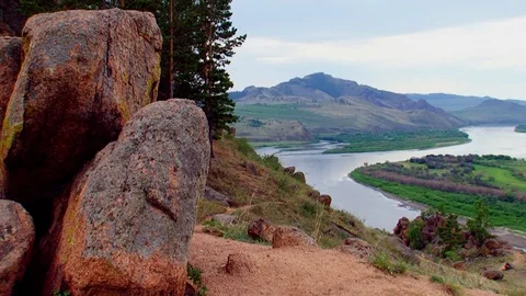Summer, day, view from the hill over the river with a rock in the foreground. Video stock 106857256