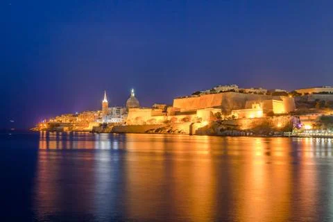 Summer deep night view of Valetta profile over sea. Long exposure. Illuminated Stock Photos