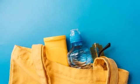 Summer essentials in yellow tote bag with water bottle and sunscreen Stock Photos