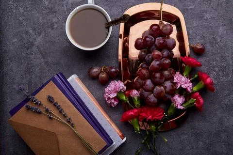 Summer flat lay breakfast with grapes, cup of coffee, books and flowers on the 스톡 사진