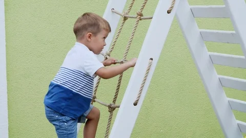 Summer, in the garden, child, a four year old boy climbs the children's stairs Stock Footage 80438948