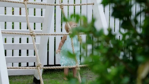 Summer, in the garden, child, a one-year-old girl is going to climb the children Stock Footage 80438906
