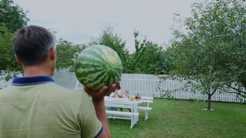 Summer, in the garden, Dad bears a large watermelon, is going to treat his Stock Footage 80439098