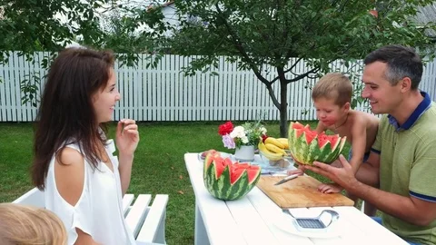 In summer, in the garden, father with a four-year-old son cut a watermelon and Stock Footage 80439666