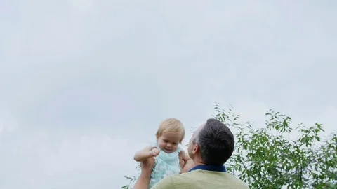 Summer, in the garden, mother, a view from below, the daddy throws his one-year Stock Footage 80439066