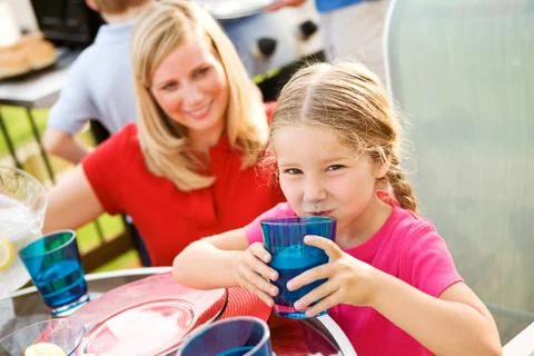 Summer: girl drinking lemonade at table Stock Photos
