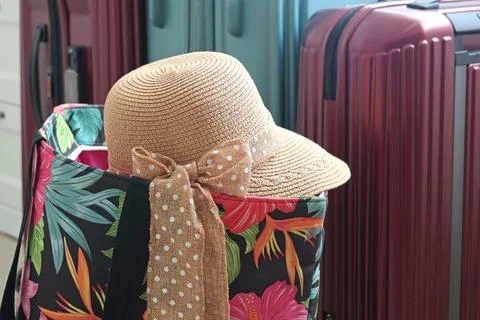 Summer hat with bow on beach bag near flip flops at home. Summer and vacation Stock Photos