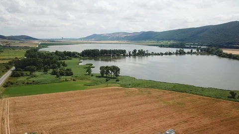 Summer landscape with fields, meadows, lake and mountains. Road on the lakeside Stock Footage 125846478