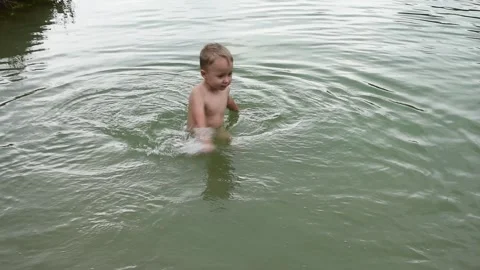 Summer leisure time, kid boy splashing in a pond and has fun, water games. Stock Footage 247457998