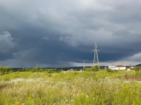 Summer meadow in the rays of the sun with an impending thundercloud and elect Stock Photos