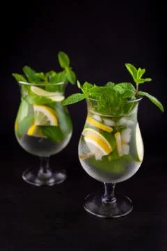 Summer mint lime refreshing cocktail mojito with rum and ice in glass on blac Stock Photos