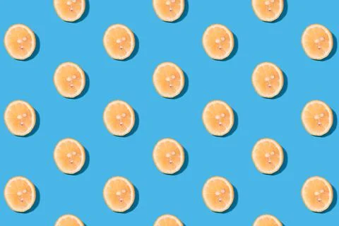 Summer pattern of yellow lemon slice on bright blue background. Stock Photos