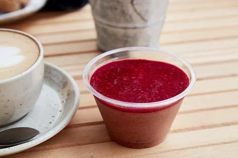 Summer pick up raspberry jam dessert in a disposable cup, a snack. Cappuccino in Stock Photos