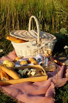 Summer picnic setting in the meadow in the rays of the sunset Stock Photos