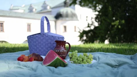 Summer picnic setup with purple basket fresh fruit watermelon and ceramic jug on Stock Footage 311130593