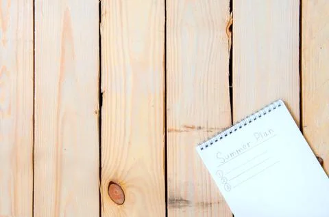 Summer Plan. Notepad with entries for summer plans on a wooden background. Stock Photos