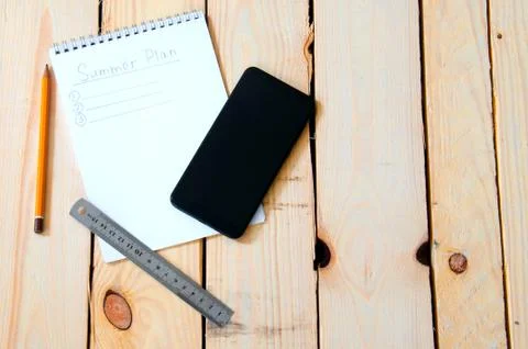 Summer plan. Notepad with notes for summer plans on a wooden background with  Foto stock