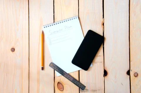 Summer plan. Notepad with notes for summer plans on a wooden background with  Stock Photos