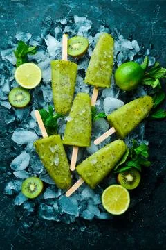 Summer popsicles with lime and kiwi. On a black stone background. Stock Photos