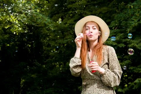 Summer portrait banner with place for text. Beautiful red haired girl blows s Stock Photos