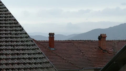 Summer rain falling on the red tile roofs and chimneys Stock Footage 83525407
