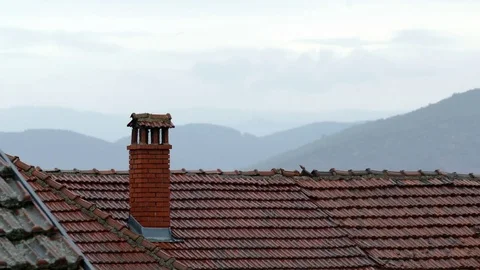 Summer rain falling on the red tile roofs and chimney Stock Footage 84524610