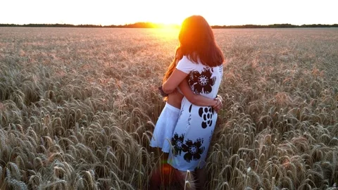 In the summer rays of the sun, mom and daughter hug on a wheat field Stock Footage 168641146