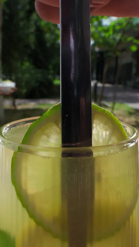 Summer refreshing drink. Garnishing summer soft drink in a glass with sliced Stock Footage 314464351