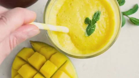 Summer refreshing healthy drink. Hand mixing mango smoothie Stock Footage 196627372