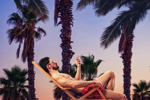 Summer relaxation at sunset by watching the mobile phone Stock Photos