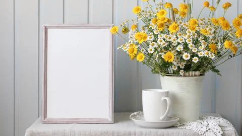 A summer rural mockup. an empty frame and a bouquet of daisies on the table i Stock-Fotos