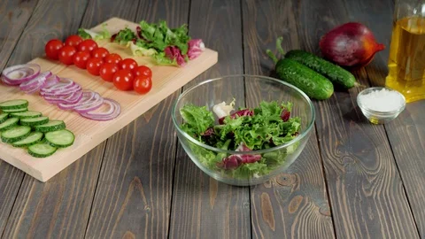 Summer salad. Professional chef pours sliced fresh green cucumbers in glass bowl Stock Footage 129746375