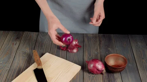 Summer salad. Woman's hand puts peeled purple onion on a light board Stock Footage 129745532