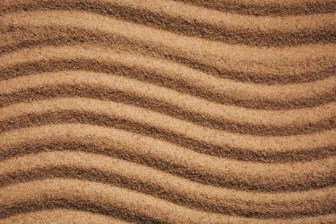 Summer sandy background or texture. Sandy waves near the sea. Stock Photos